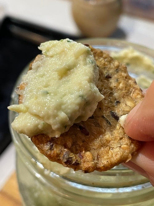 On the left a jar with mixed lemon pith and a stick blender in the jar. On the left a cracker with the finished fermented lemon pith dip.