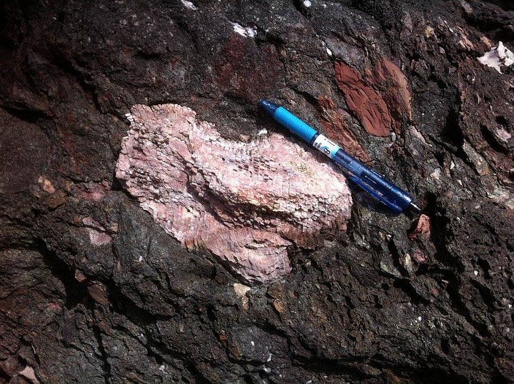 First image: outcrop of tan-colored rock on top of grey-colored rock. The boundary between the two is marked by a pen. Second image: a piece of white coral surrounded by black and red volcanic debris. A pen is included for scale.