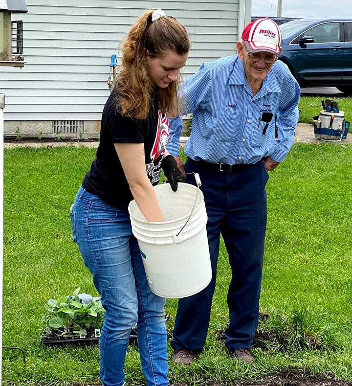 Author's young adult daughters helping her father plant a garden.