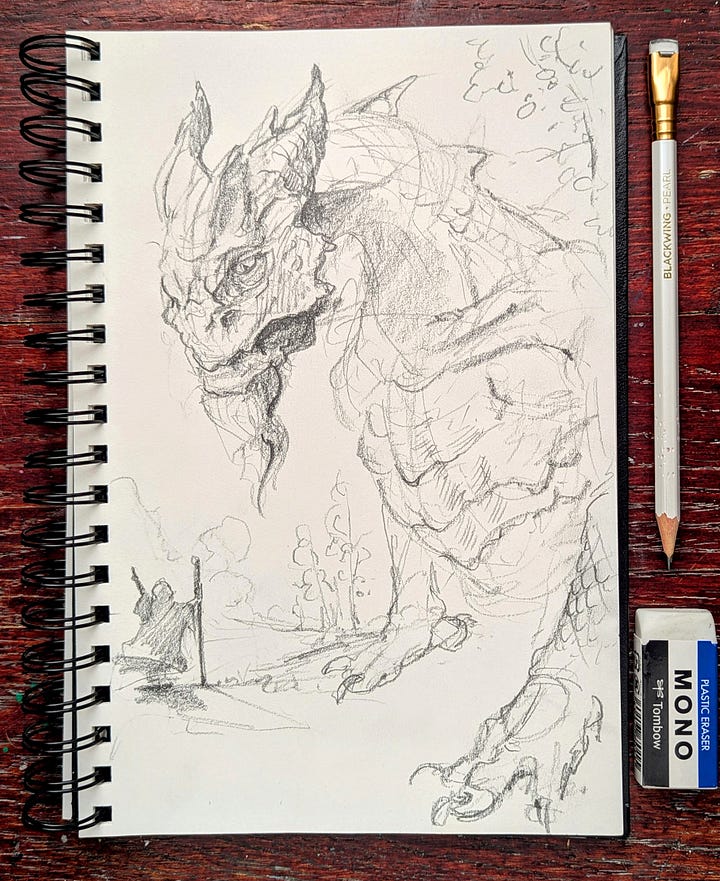 A sketchbookona table open to a sket of a dragon and a page of thumb-nailed compositions