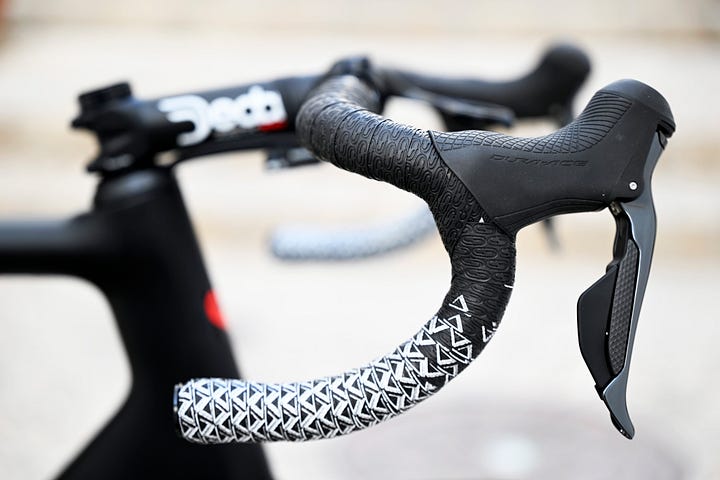 A collection of close up images, describing the components of Bingoal Wallonie Bruxelles De Rosa Merak 2023 edition racing bike. Featuring Hutchinson tyres, Shimano Dura Ace 11 speed groupset, Ursus wheelset, Deda cockpit and bar tape and Bryton headunits. Topped off with Swissstop braking system.