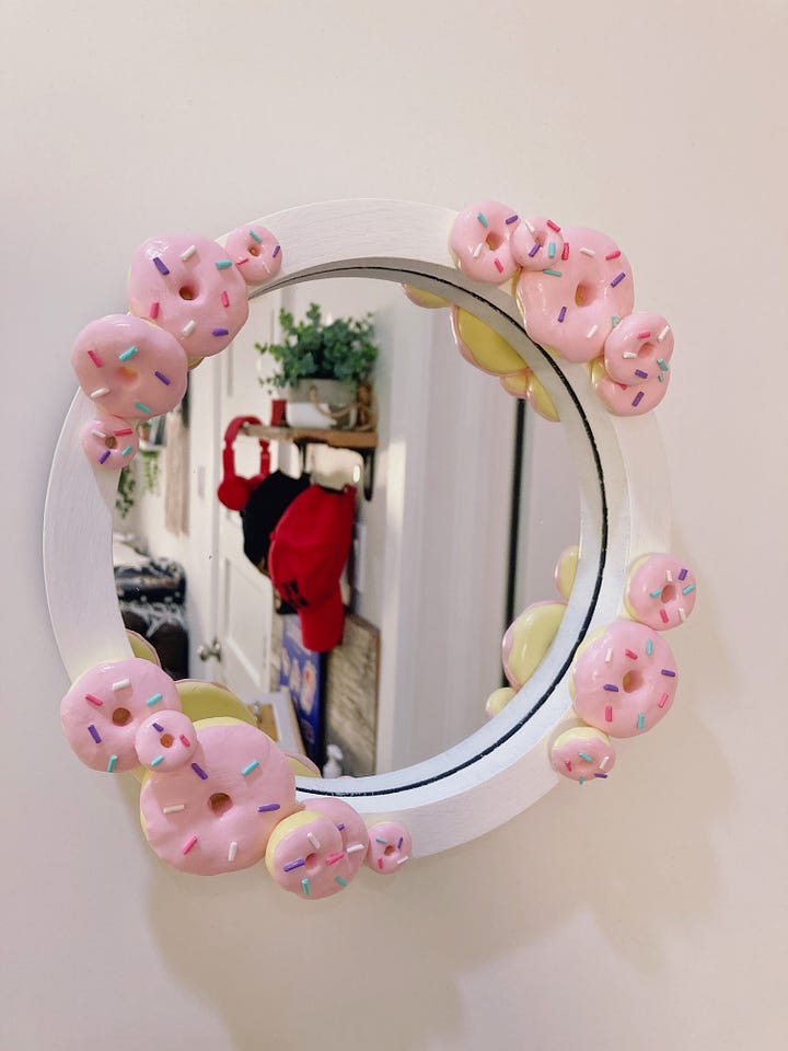 One mirror has stacks of donuts around the frame and the other is pink with strawberries painted all around the frame.