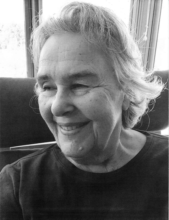 Selfie photo facing left; pencil self-portrait facing right. Smiling old woman with short frowsy gray hair.