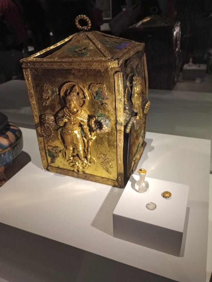 Left, gilded bronze box embossed with image of Buddha, right: lidded stone jar, and decorated earthenware jar