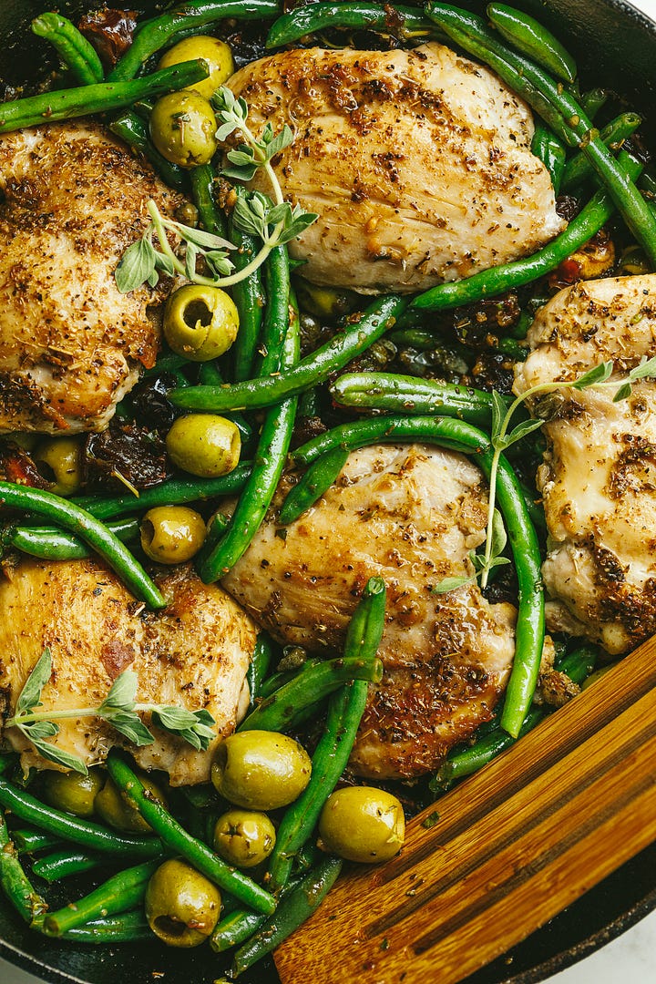Green beans, olives, and dates in a pan; chicken nestled into the vegetables.