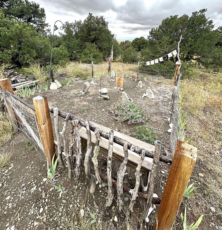 On the left, several headstones inside a wrought iron fence. On the right, rocks and headstones within a wooden fence. 