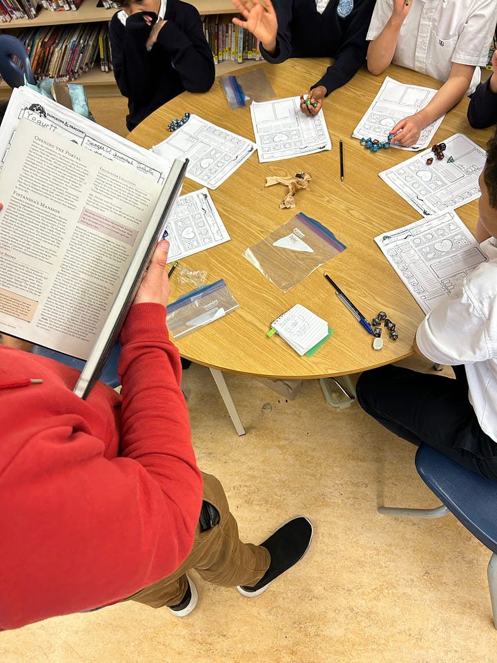 Students sitting around a round table with character sheets, dice and pencils laid out in front of them.