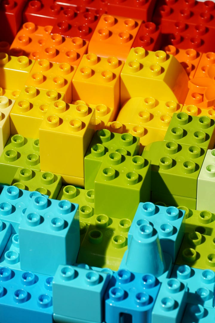 Left image is a small green and yellow frog facing the camera and looking like he's getting ready to take a big leap. Image on right is a stack of multicolor legos, also in vibrant yellow and green.