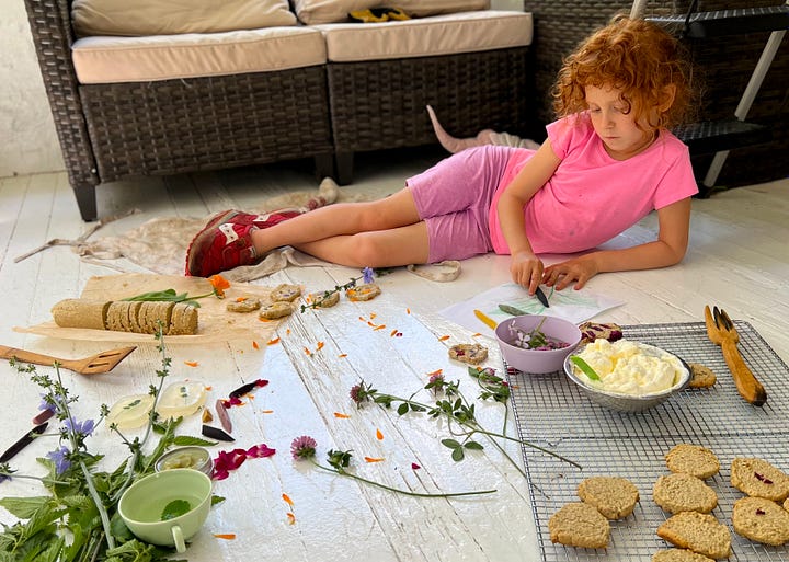 Children pressing edible flowers onto oatcake cookies, a shortbread-like biscuit.