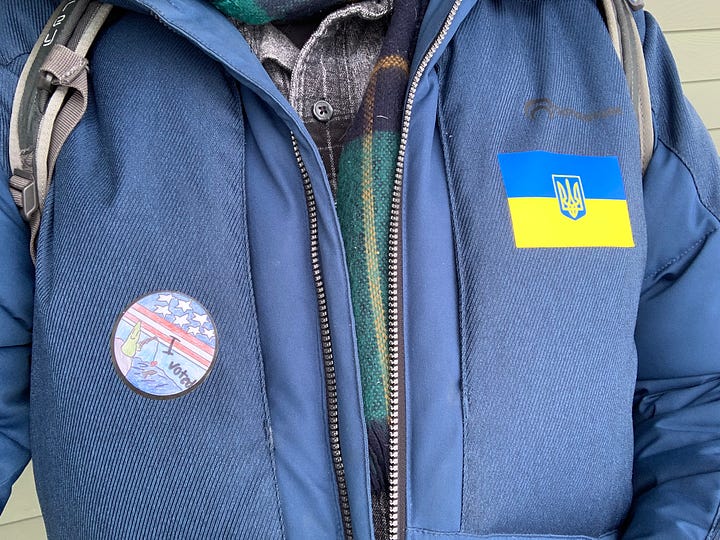 photo 1 of "I voted" sticker and Ukrainian flag sticker on coat. Photo 2 of a polling station sign. Photo 3 of a Joe Biden advocate holding a sign. Photo 4 of a Dean Phillips advocate holding a sign.
