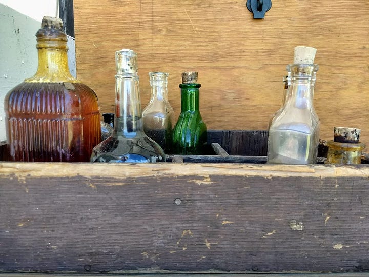 Inside of covered wagon, filled with boxes, coffee pot,, and baskets. Other photo shows glass bottles in box