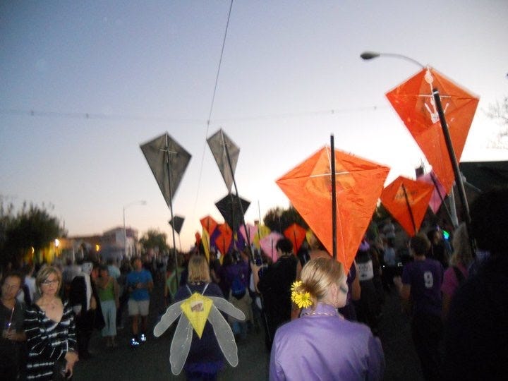 Steph in a purple button-down and tie, face painted like a skeleton, and the All Souls parade at night.