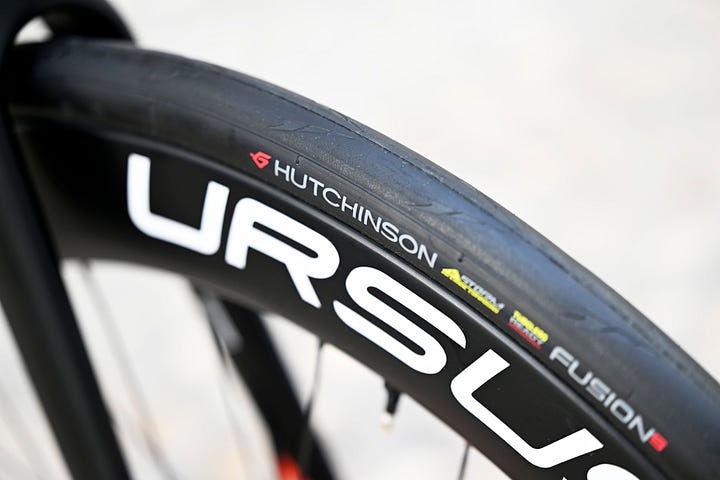 A collection of close up images, describing the components of Bingoal Wallonie Bruxelles De Rosa Merak 2023 edition racing bike. Featuring Hutchinson tyres, Shimano Dura Ace 11 speed groupset, Ursus wheelset, Deda cockpit and bar tape and Bryton headunits. Topped off with Swissstop braking system.