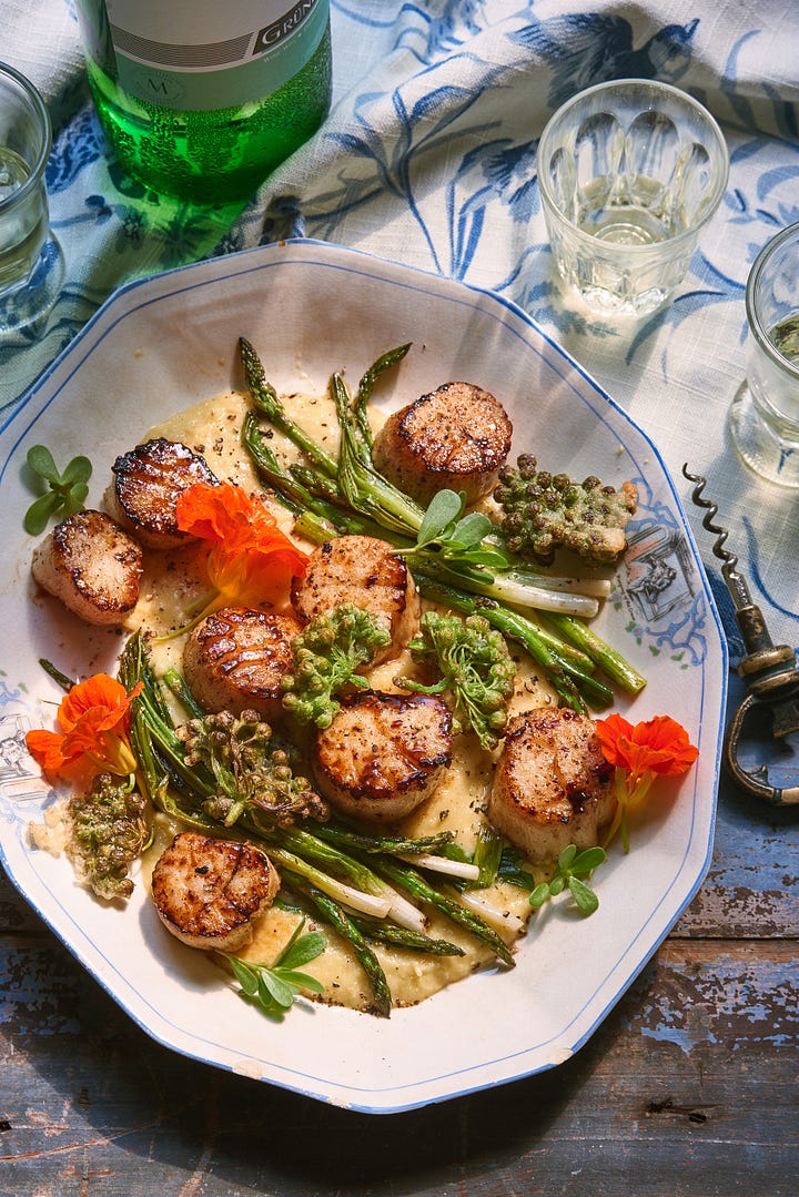 4 images of different plated dishes that Melina cooked and styled. The top left is a fresh pasta with peas, the top right is a cake with bright red plums on top, the bottom left is scallops with asparagus and nasturtiums, and the bottom right is of beans on toast with arugula and a jammy egg opened up on top 