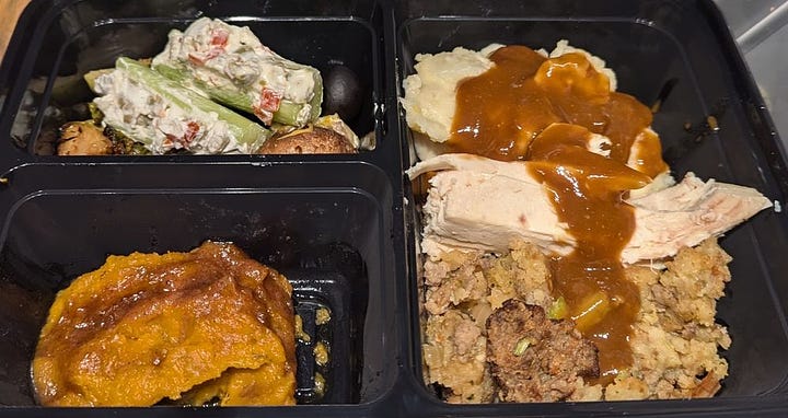 A thanksgiving plate including turkey and stuffing and mashed potatoes and gravy and some other stuff I can't identify. Plus another plate with slices of apple and pumpkin pie.