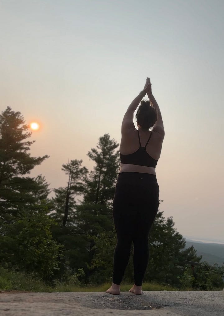 A gallery of images shows a woman standing on a mountain top with the rising sun in the background doing a series of yoga poses.