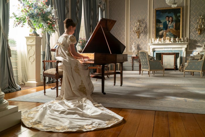 The Bridgerton family stand listening at a door. And Francesca Bridgerton plays a grand piano.