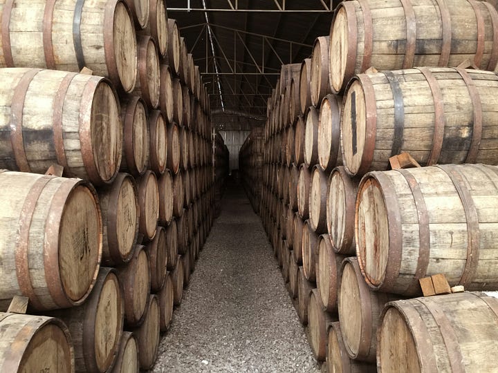 A bottle of Neta mezcal. Barrels of Tequila being aged - photo Fred Crandon via Unsplash.