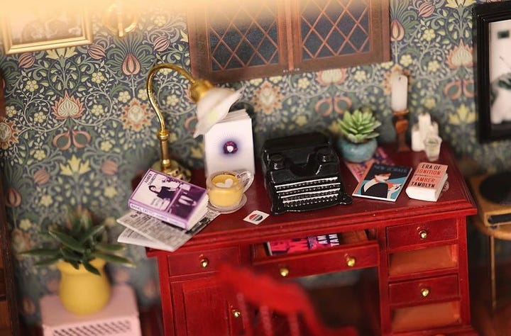 Close up images of the miniature room. Books Amber has written, the "Y: The Last Man" graphic novel, a photo of her husband, a typewriter, and tarot cards can be seen.