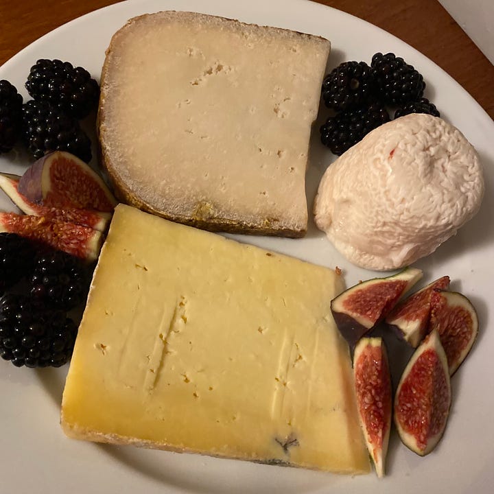 Selections of whole & sliced cheeses, some hard, some squidgy, some very ripe with ripe figs, blackberries and grapes
