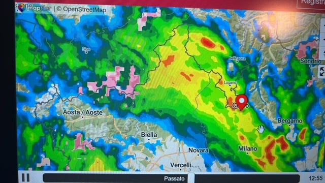 weather radar of rain in italy, open window in a northern italian home with clouds and rain outside and legs under the covers of a bed inside