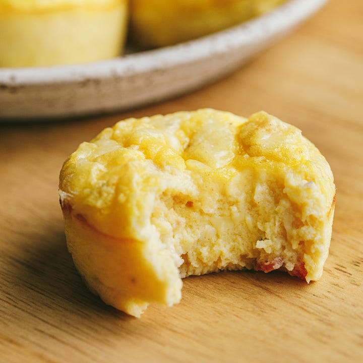 Egg bites in a silicone muffin pan; a bite taken out of one.