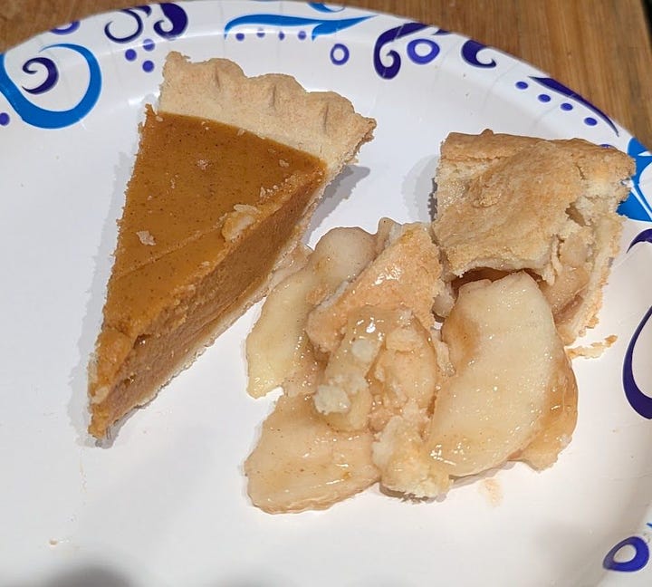 A thanksgiving plate including turkey and stuffing and mashed potatoes and gravy and some other stuff I can't identify. Plus another plate with slices of apple and pumpkin pie.