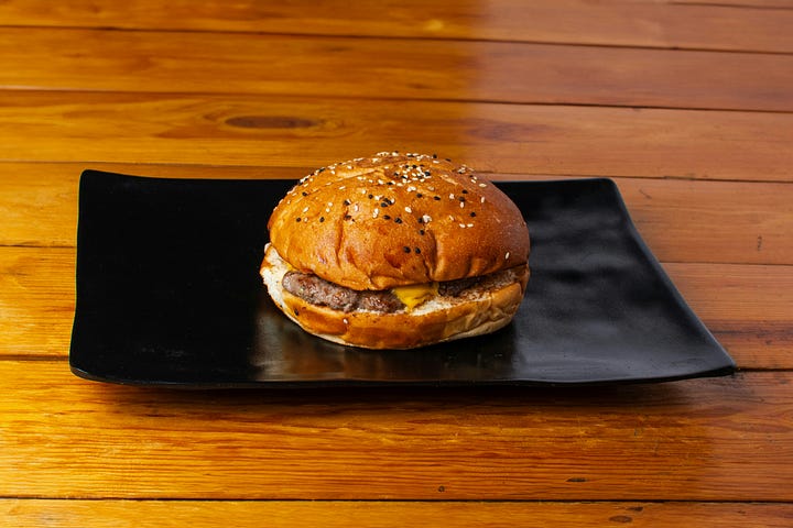 "J'Existe" written on steps and a burger. Photos by Nicolas Mastrogiacomo and Fotografía de Alimentos via Unsplash.