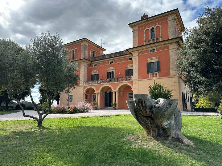 The image on the left shows a beautiful fountain surrounded by flowers and lilypads. There are tall trees in the distance and a hotel up on the hill behind it. The photo on the right shows a big bright orange and cream colored villa, with 3 archways at the entrance and many windows. There is a green lawn in front of it, with some pomegranate trees. 