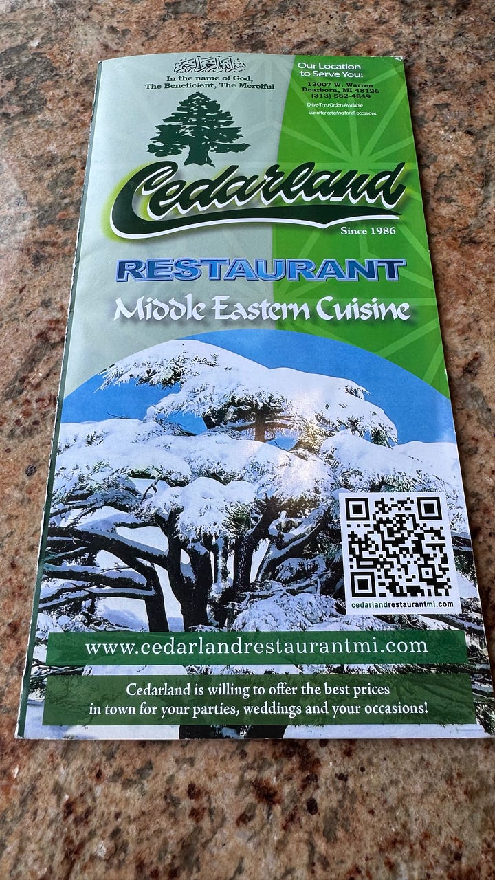 1. The front cover of the Cedarland menu. A photo of Cedar trees with the words "Cedarland. Middle Eastern Cuisine." 2. A chicken shawarma pita wrap with a bit taken out of it. 3. A plate with tabbouleh salad and a fork. 4. A plate with a large mound of hummus and another with a large mound of baba ghanouj