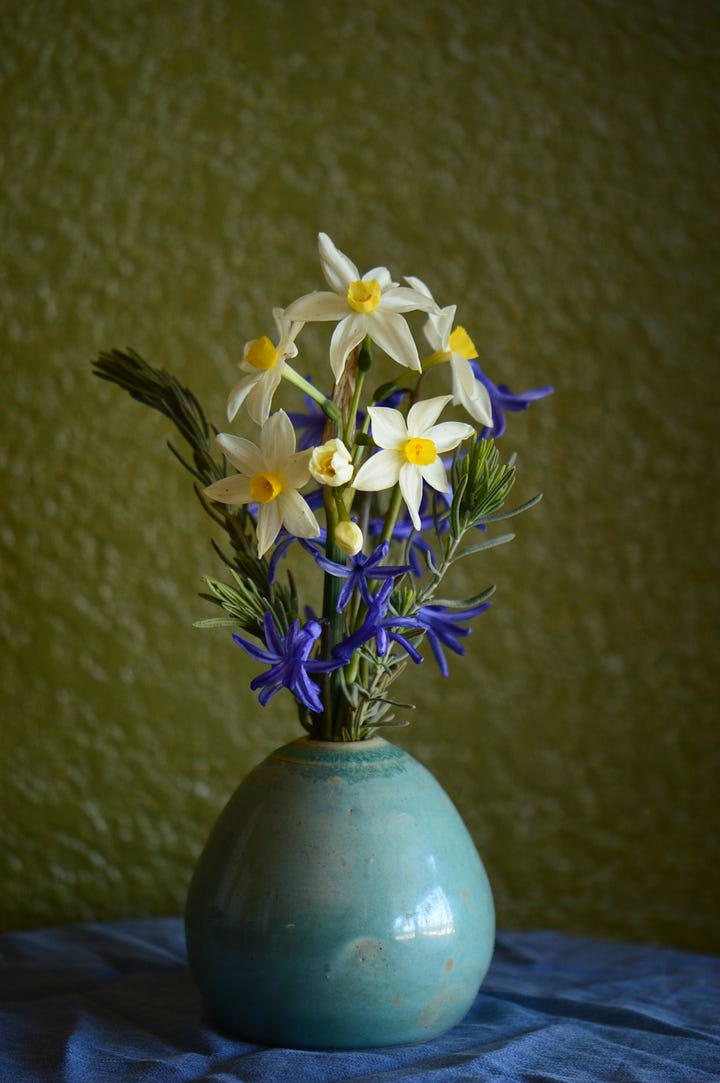 White and yellow Narcissus with blue Roman hyacinths in a pale blue art vase