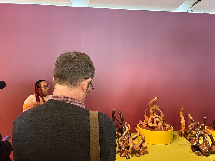 A museum display with words "Genealogies of Sustenance" in a mustard yellow against a burgundy background.