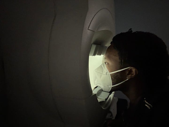 (Image 1) A photo of a beige computer-machine with a keyboard in front of it. (Image 2) ArmaniXR sits with his chin rested on a large, beige machine. He looks through it as soft light glows on his face.