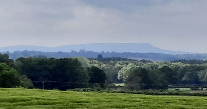 Two images of a distant hill, rising above the countryside