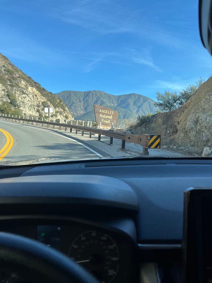 On the right, a brown sign with beige writing reads Angeles National Forest. On the right is a photo of native California plans (names of the plants are unknown)