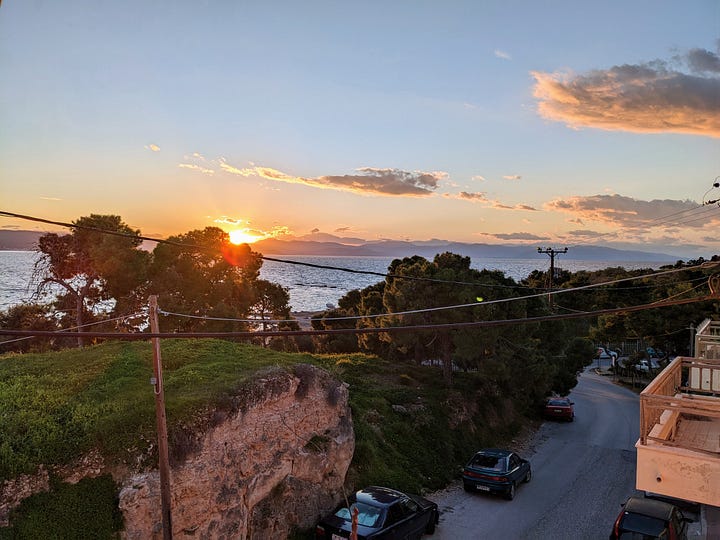 Pictures of the sun setting over the ocean with land in the background