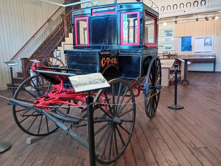 Horse=drawn four-wheel cab, photo of large wooden building with people and horses