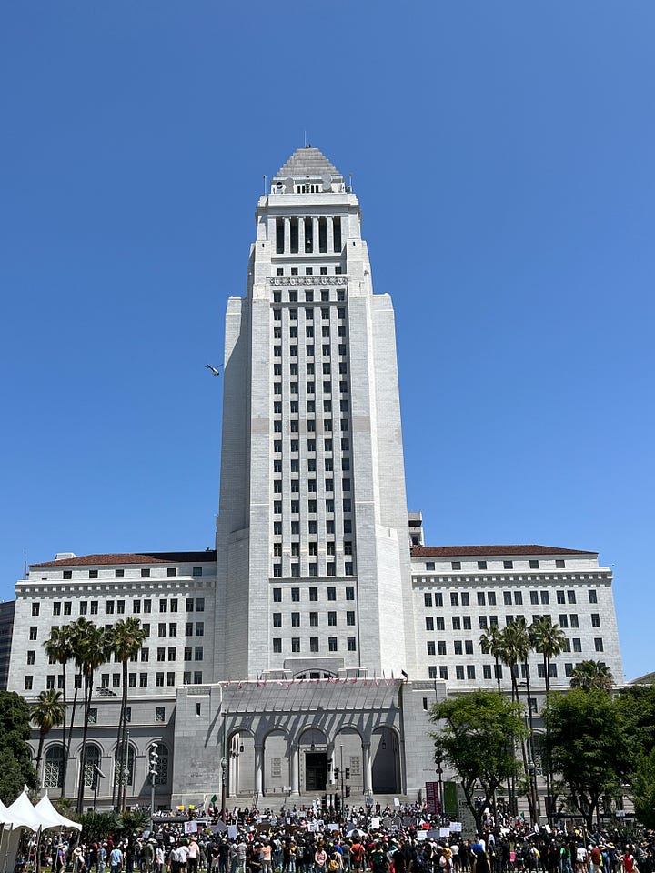 Two photos. One shows a masked woman dressed as Princess Peach. She is wearing a sign that states: "IM PEACH". The other photo shows LA City Hall with a crowd of protestors in front of it.