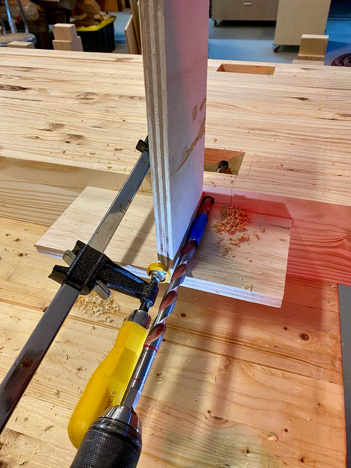 Drilling holes in the side of a workbench top, then filling holes with dowels and making new holes.