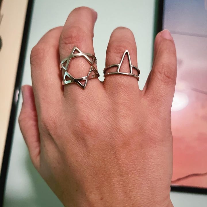 A Jewish woman in glasses showing off two rings on her right hand; a hand wearing a Magan David ring on the middle finger