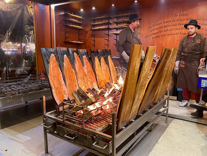 Ferris Wheel and big Christmas tree at the Christmas market in Bonn, Germany, and ten whole salmon being smoked over an open fire.