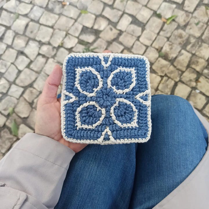 Overlay mosaic crochet squares made center-out, one with a flower design in white on denim blue; two in burgundy and navy-blue with a geometric design.