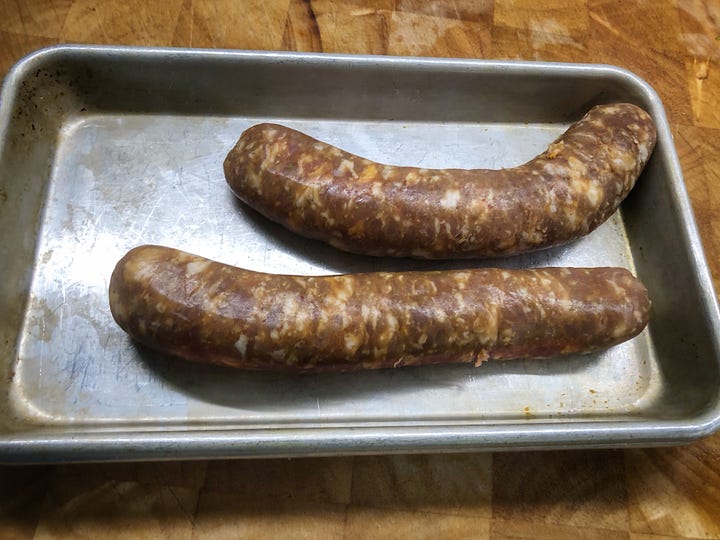 A gallery of four images. 1: Sausages that have had their casings removed 2: Chopped rapini in a colander. It is wet from rinsng. 3: A bowl of grated Parmesan cheese beside the grater and a hunk of cheese 4: Minced garlic in a small prep bowl