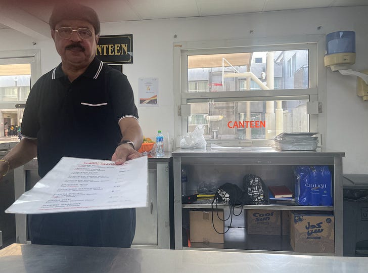 Noel, who manages a canteen at St. Mary's Catholic Parish, offers a visitor a menu of lunch items. Credit: JD Flynn/Pillar Media.