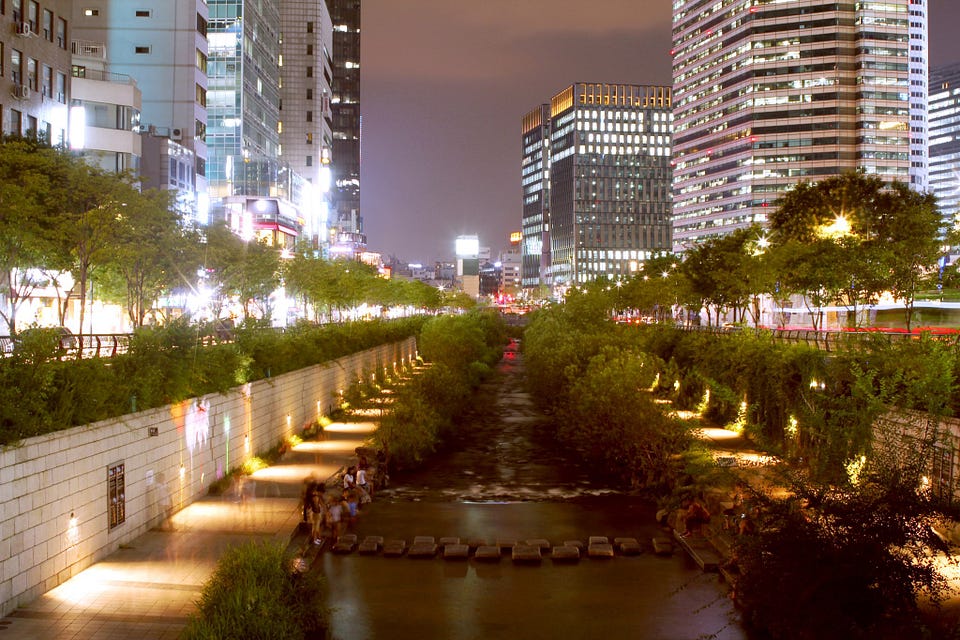 Seoul’s Cheonggyecheon at night: a restored stream with stepping stones and lit walkways below office towers
