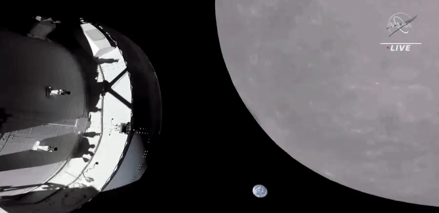 An animation of frames from NASA TV showing the small blue and white disc of the distant Earth setting behind the mottled grey globe of the Moon (which is positioned across much of the right side of the frame). The Orion spacecraft and service module appear across the left hand side of the frame. 